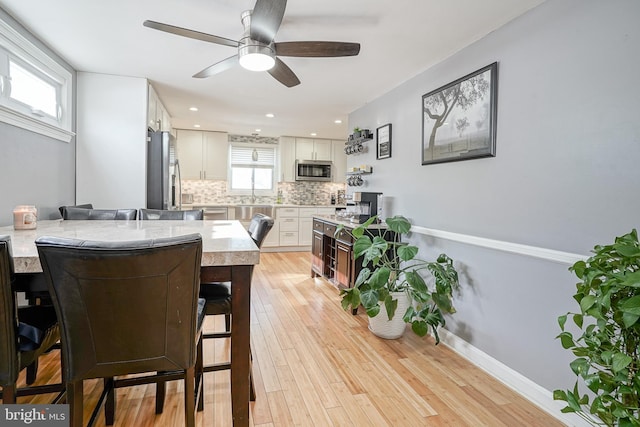 dining space with ceiling fan and light hardwood / wood-style flooring