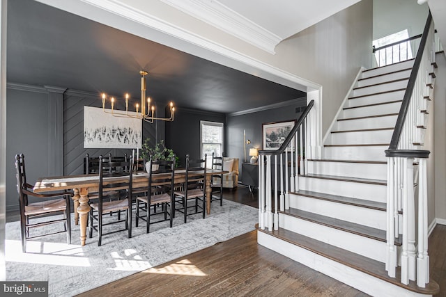 dining room with dark wood-type flooring, ornamental molding, and a notable chandelier