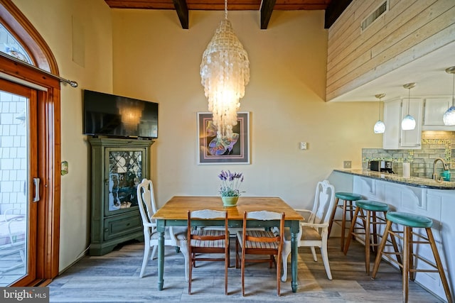 dining room featuring sink, wood ceiling, hardwood / wood-style flooring, beamed ceiling, and a chandelier