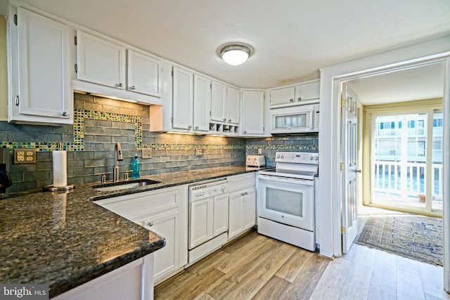 kitchen featuring sink, light hardwood / wood-style flooring, white appliances, dark stone counters, and white cabinets