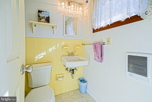 bathroom with heating unit, sink, tile walls, toilet, and tile patterned floors