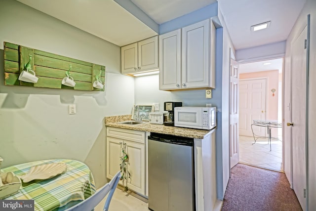 kitchen with sink, light carpet, light stone counters, and refrigerator