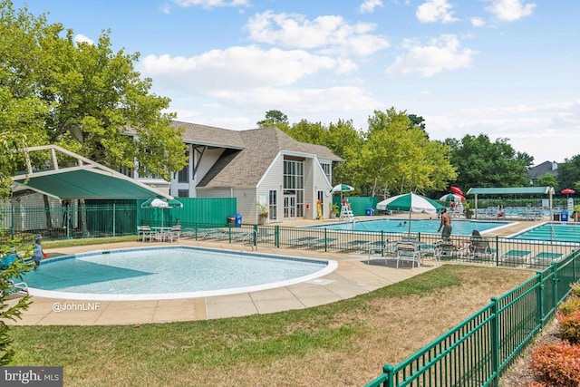 view of pool with a patio and a lawn