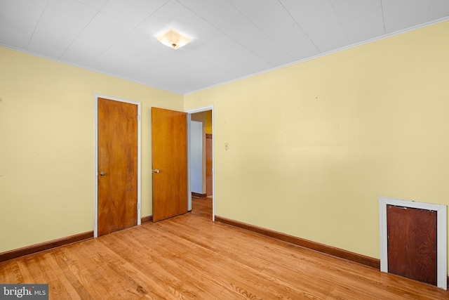 empty room with ornamental molding and light wood-type flooring