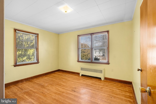 unfurnished room with crown molding, radiator heating unit, and light wood-type flooring