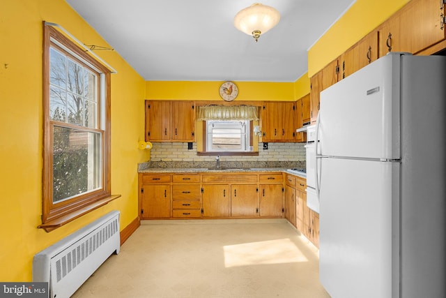 kitchen featuring radiator, sink, black gas cooktop, white refrigerator, and decorative backsplash