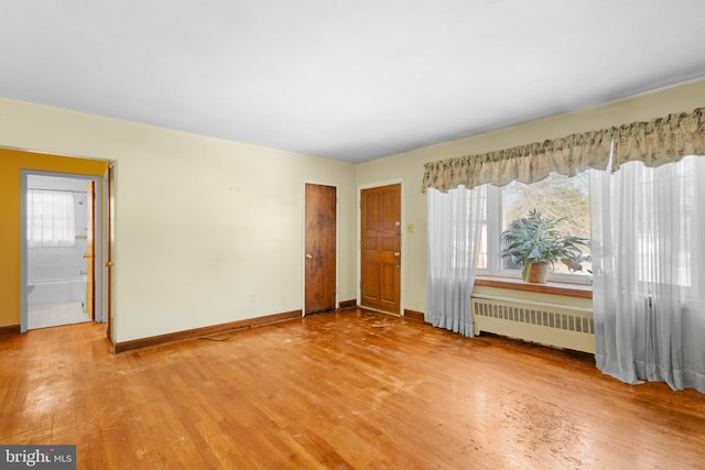 empty room featuring wood-type flooring, radiator, and a wealth of natural light