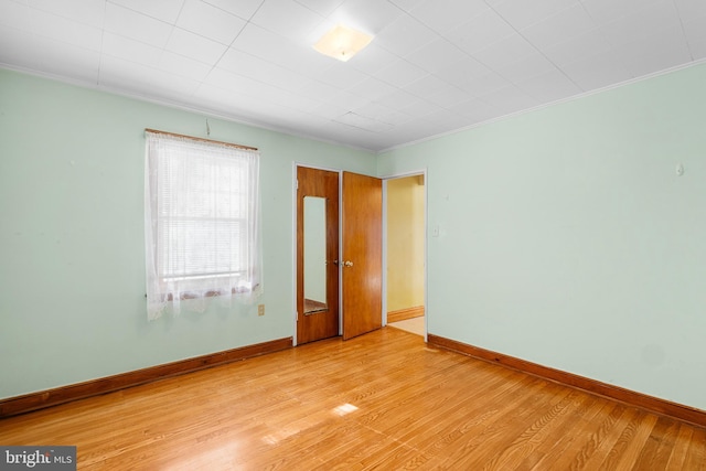 empty room with crown molding and light hardwood / wood-style flooring