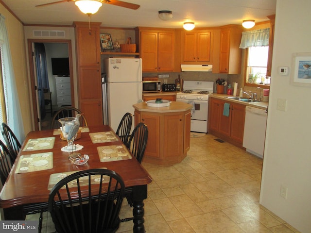 kitchen with ceiling fan, a kitchen island, sink, white appliances, and ornamental molding