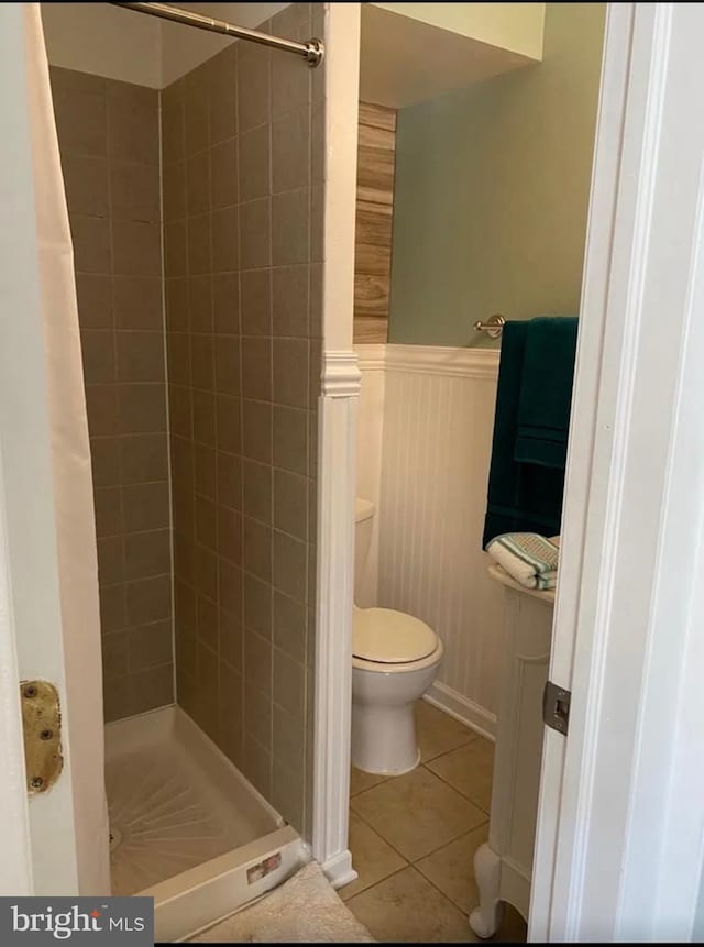 bathroom with toilet, tile patterned floors, and tiled shower