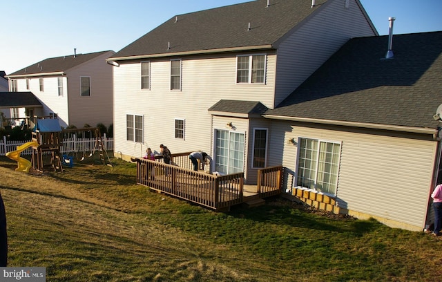 back of property featuring a wooden deck, a yard, and a playground