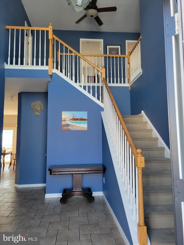 staircase with ceiling fan and a towering ceiling