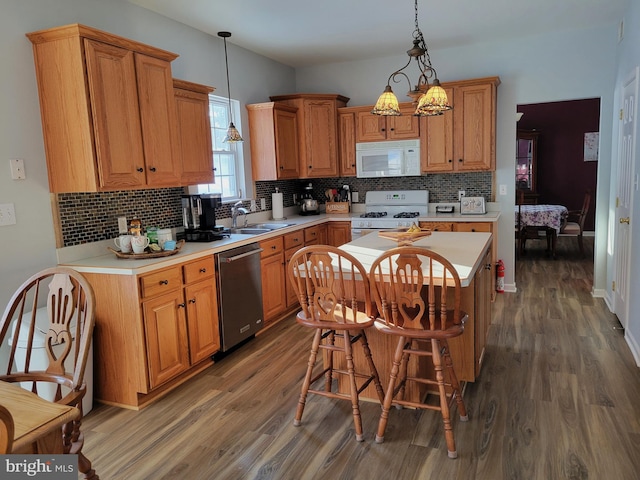 kitchen with a kitchen island, decorative light fixtures, sink, dark wood-type flooring, and white appliances