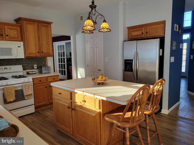 kitchen featuring tasteful backsplash, hanging light fixtures, white appliances, and a healthy amount of sunlight