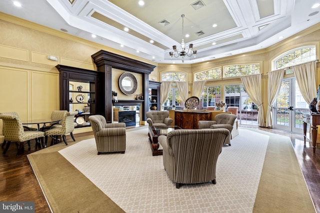 living room with crown molding, a tiled fireplace, an inviting chandelier, and a high ceiling