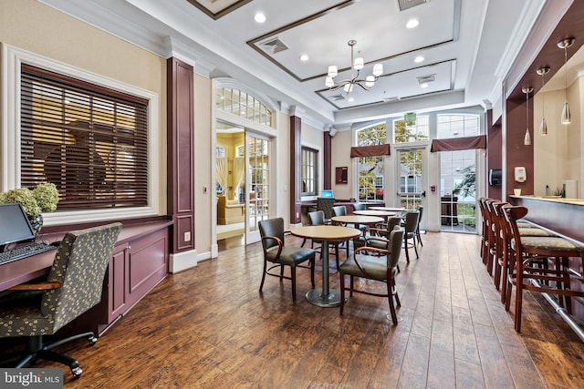 dining area featuring crown molding, dark hardwood / wood-style floors, an inviting chandelier, and a tray ceiling