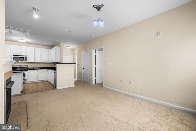 kitchen featuring appliances with stainless steel finishes, white cabinetry, hanging light fixtures, light colored carpet, and track lighting