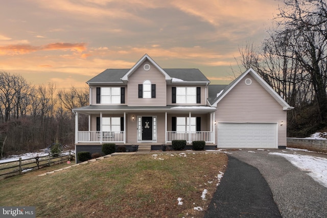 view of front of home with covered porch, a garage, and a yard