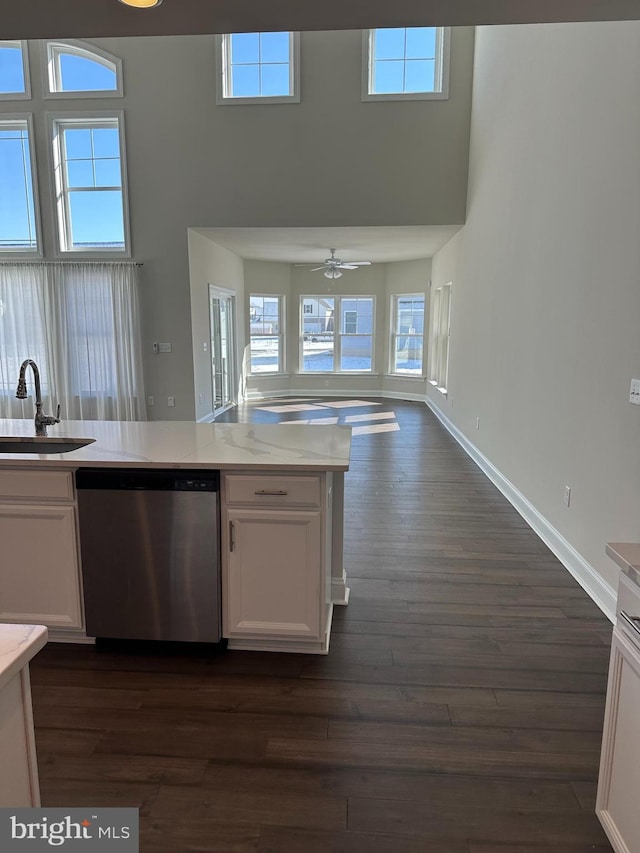 kitchen featuring sink, stainless steel dishwasher, a towering ceiling, and white cabinets