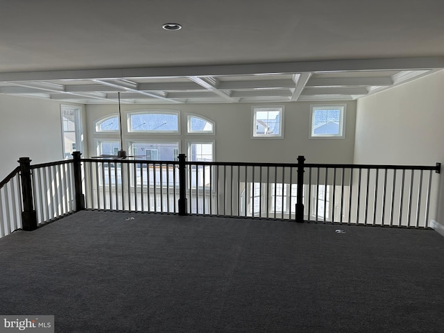 empty room featuring coffered ceiling, carpet floors, and beam ceiling