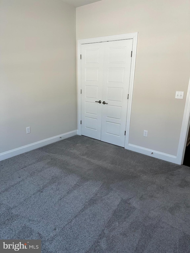 unfurnished bedroom featuring dark colored carpet and a closet