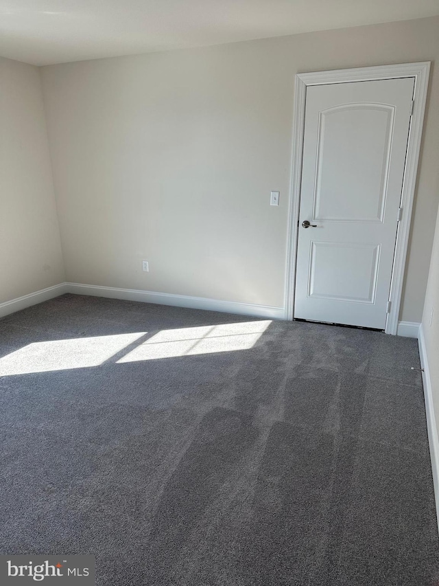 unfurnished room with dark colored carpet