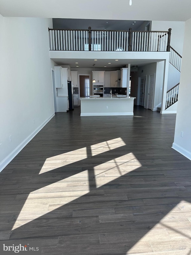 unfurnished living room with a high ceiling and dark hardwood / wood-style flooring