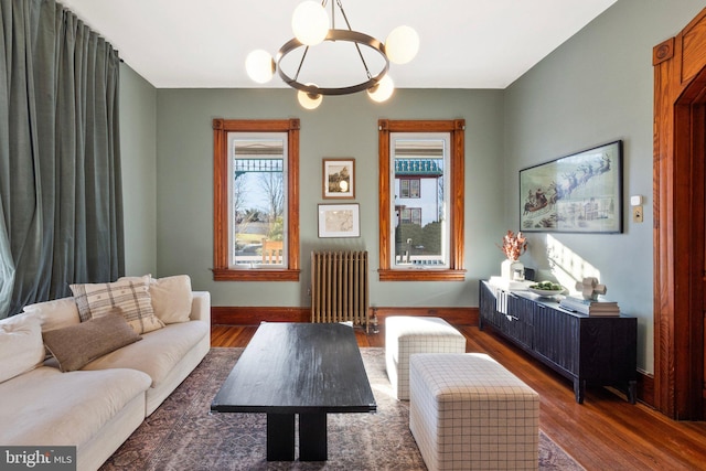 sitting room with dark hardwood / wood-style flooring, radiator heating unit, and a chandelier