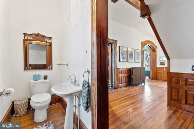 bathroom with hardwood / wood-style floors, lofted ceiling with beams, and toilet