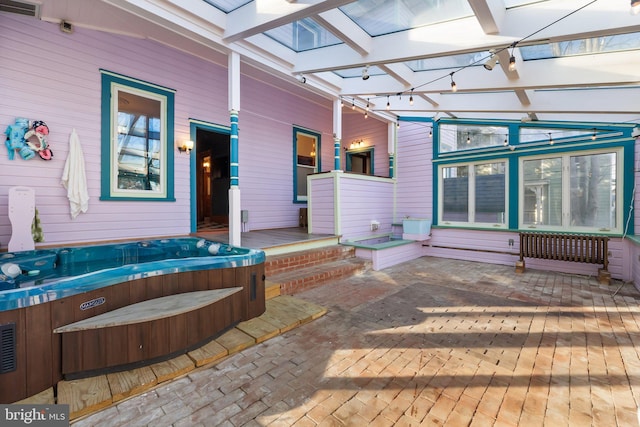 sunroom featuring radiator heating unit, a jacuzzi, and a skylight