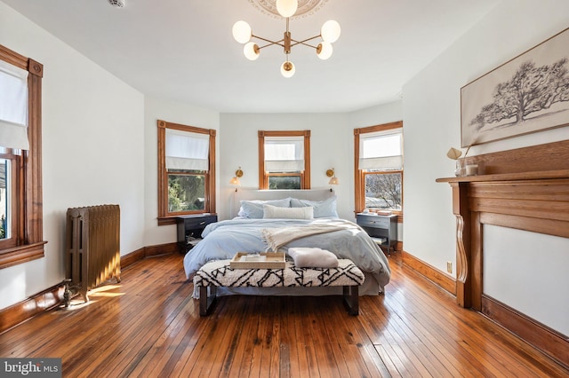 bedroom featuring hardwood / wood-style flooring, radiator, and a chandelier