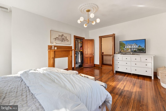 bedroom with a walk in closet, an inviting chandelier, and dark hardwood / wood-style flooring