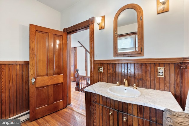 bathroom featuring vanity, wooden walls, hardwood / wood-style floors, and baseboard heating