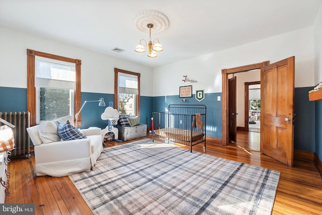 sitting room featuring hardwood / wood-style flooring, radiator, and a notable chandelier