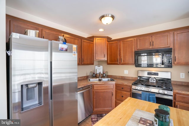 kitchen with sink, light tile patterned floors, stainless steel appliances, and wooden counters