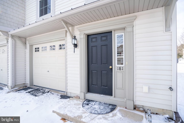 snow covered property entrance featuring a garage