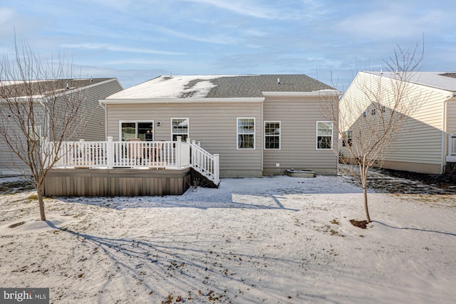 snow covered back of property featuring a wooden deck