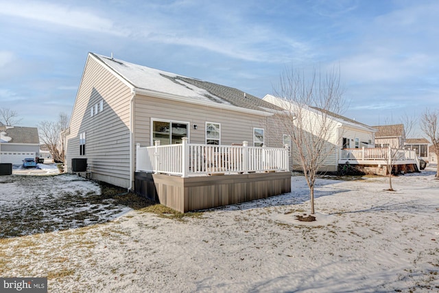 snow covered rear of property with a deck and central AC