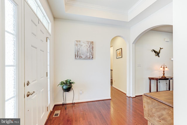 entryway with crown molding, dark hardwood / wood-style floors, and a tray ceiling