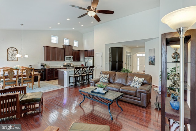 living room with ceiling fan, high vaulted ceiling, and dark wood-type flooring