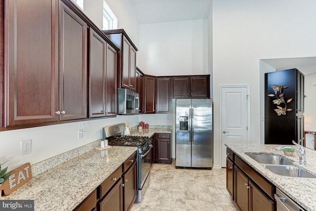 kitchen with light stone countertops, sink, dark brown cabinetry, and appliances with stainless steel finishes