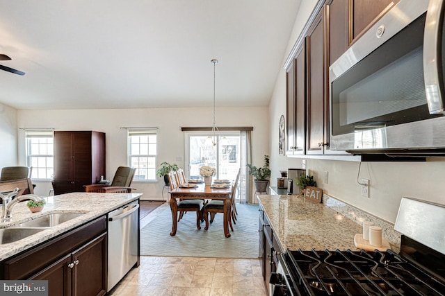 kitchen with light stone countertops, hanging light fixtures, stainless steel appliances, and dark brown cabinets