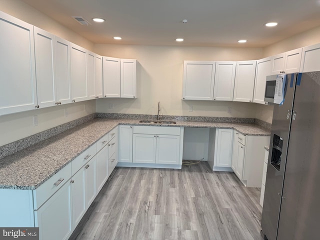 kitchen featuring white cabinetry, stainless steel appliances, light stone countertops, light hardwood / wood-style flooring, and sink