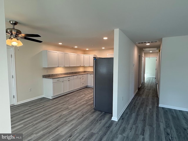 kitchen with dark wood-type flooring, stainless steel refrigerator, white cabinets, and ceiling fan