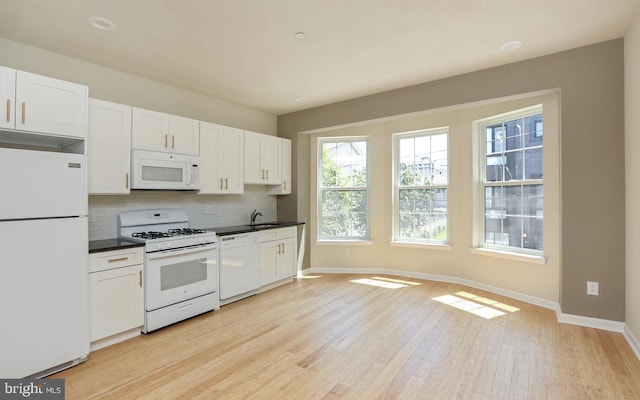 kitchen with white cabinets, decorative backsplash, sink, and white appliances