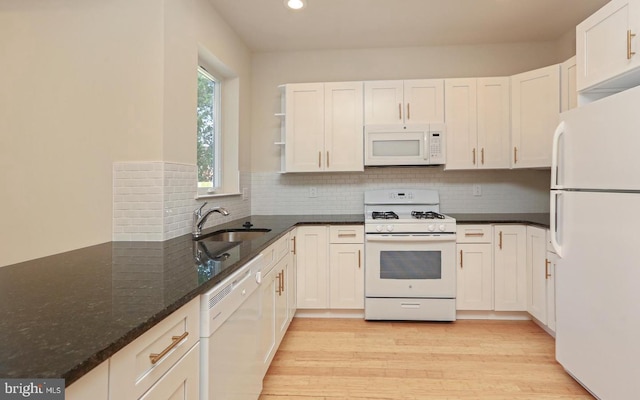 kitchen with white cabinetry, sink, white appliances, and dark stone counters