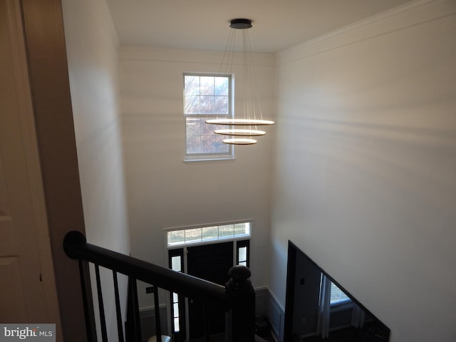 stairs with ornamental molding and a notable chandelier