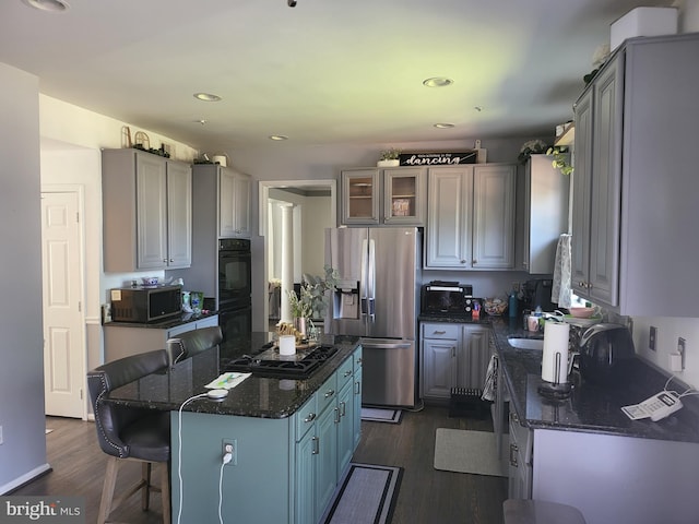 kitchen featuring gray cabinetry, a kitchen bar, black appliances, a kitchen island, and dark hardwood / wood-style flooring