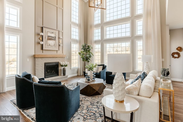 living room featuring a brick fireplace, a towering ceiling, and light wood-type flooring