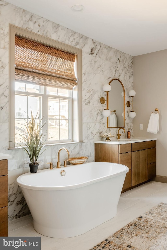 bathroom with vanity, a bathtub, and tile walls